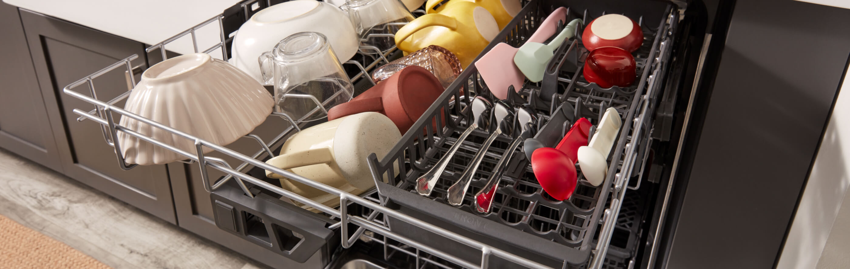 Third rack of a KitchenAid® dishwasher filled with utensils, bowls and mugs