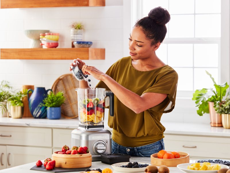 Person blending fruit in KitchenAid® blender 