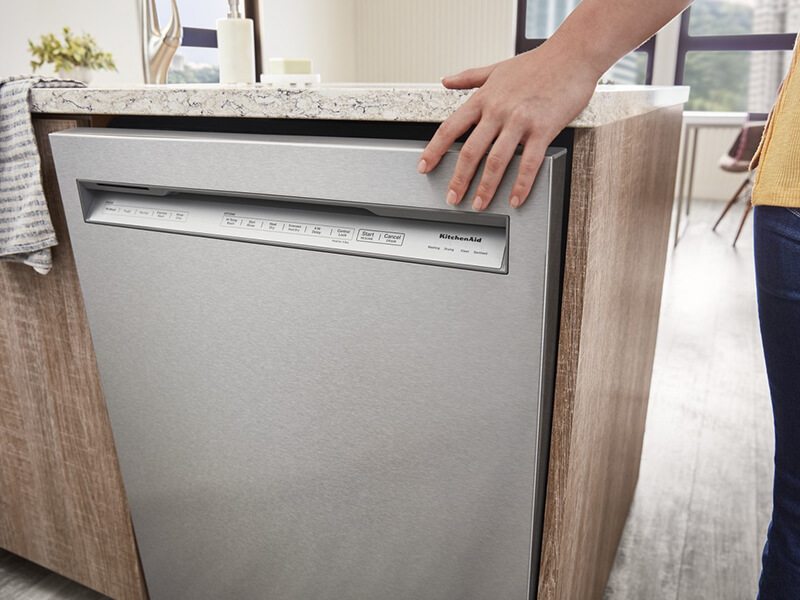 Person closing a front control dishwasher