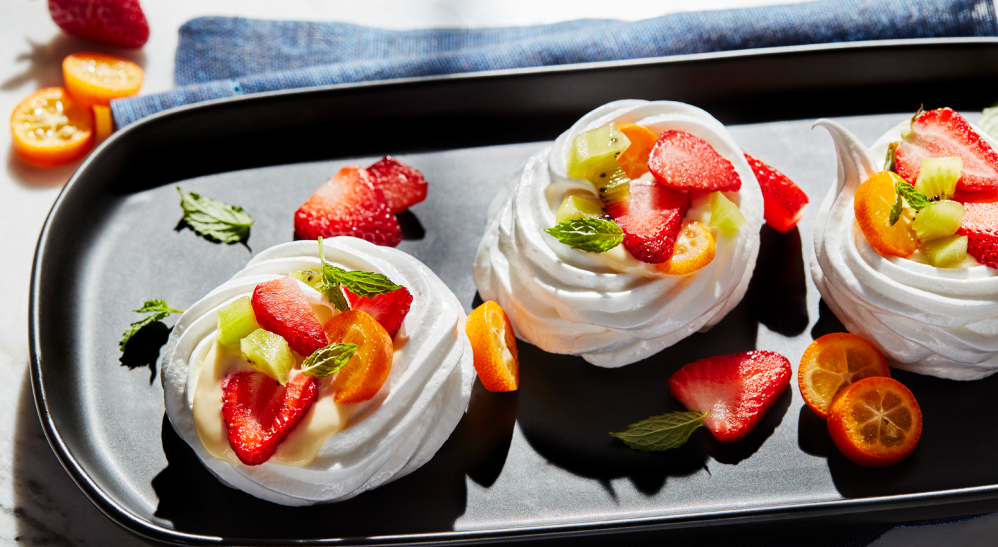 Mini pavlovas topped with sliced fruit Mini pavlovas topped with sliced fruit