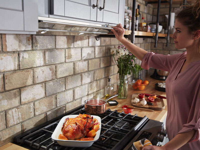 Person adjusting settings on an undercabinet hood
