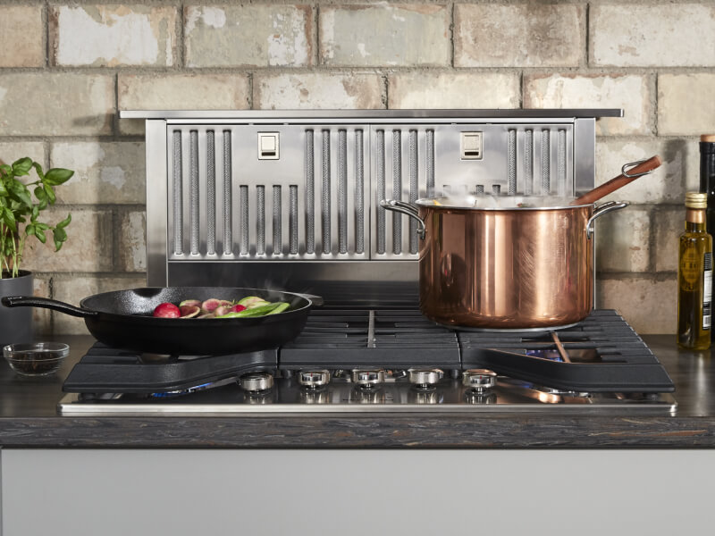 Retractable downdraft hood behind a gas range