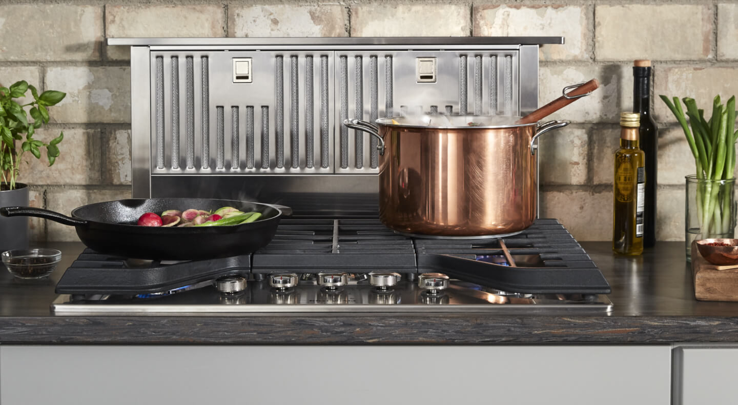 Retractable downdraft hood behind a gas range