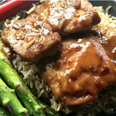 A plate of baked chai teriyaki chicken thighs over rice