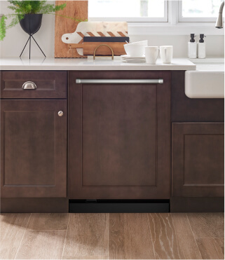 A KitchenAid® dishwasher surrounded by dark brown cabinets