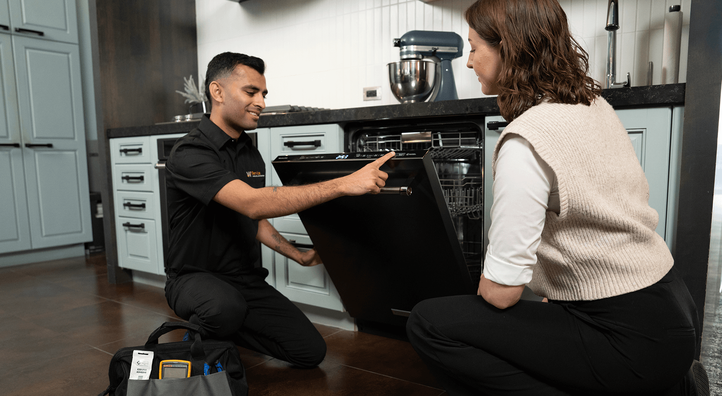 A technician helps a woman with her dishwasher A technician helps a woman with her dishwasher