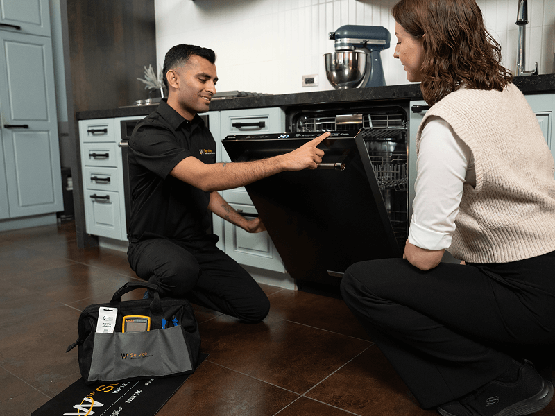 A technician helps a woman with her dishwasher A technician helps a woman with her dishwasher