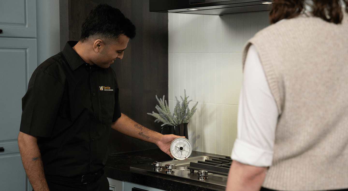 A technician helps someone with their cooktop A technician helps someone with their cooktop