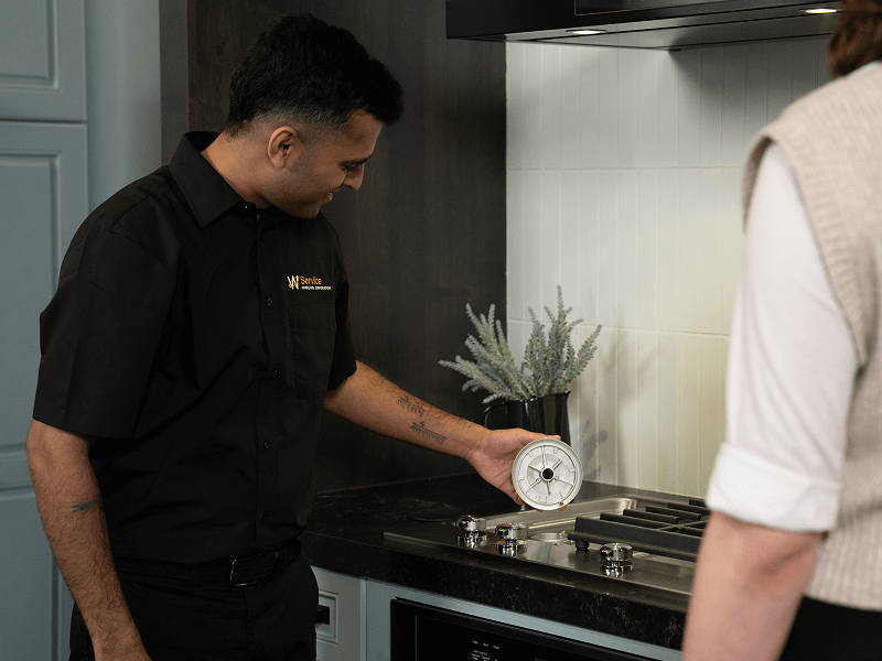 A technician helps someone with their cooktop A technician helps someone with their cooktop