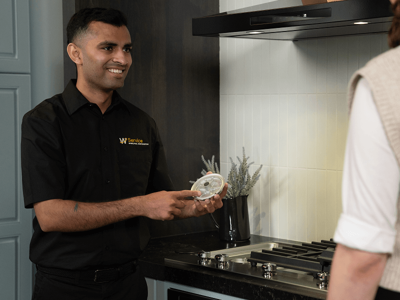 A technician helps someone with their cooktop A technician helps someone with their cooktop