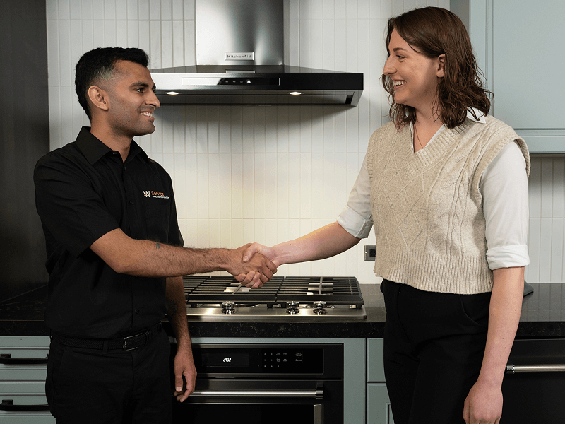 A technician helps a person in their kitchen A technician helps a person in their kitchen