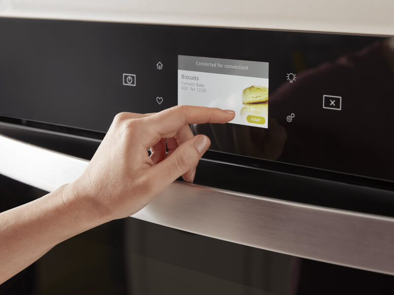 Finger pushing the LCD touchscreen display on a wall oven