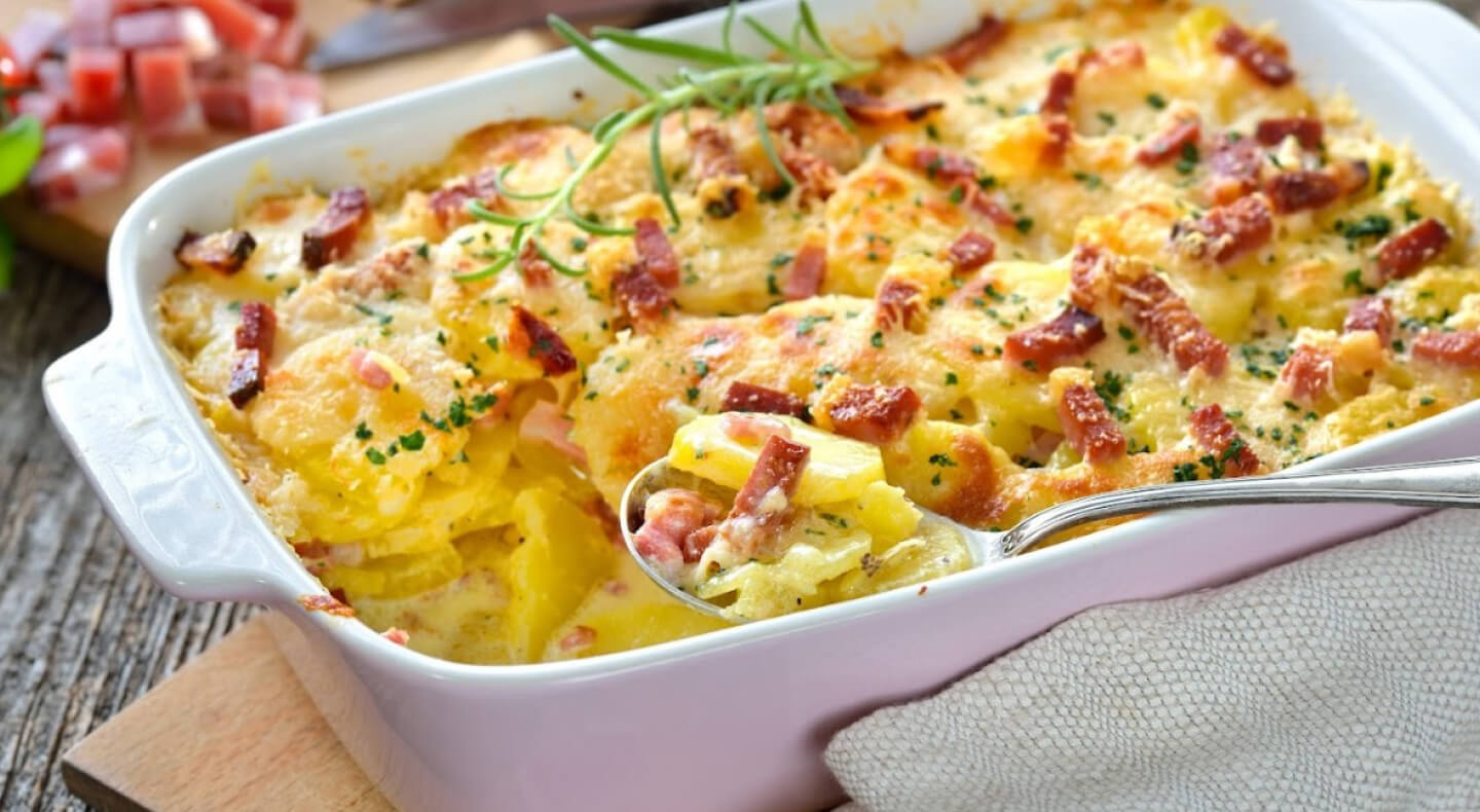 Spoon in an au gratin dish inside a white casserole pan Spoon in an au gratin dish inside a white casserole pan