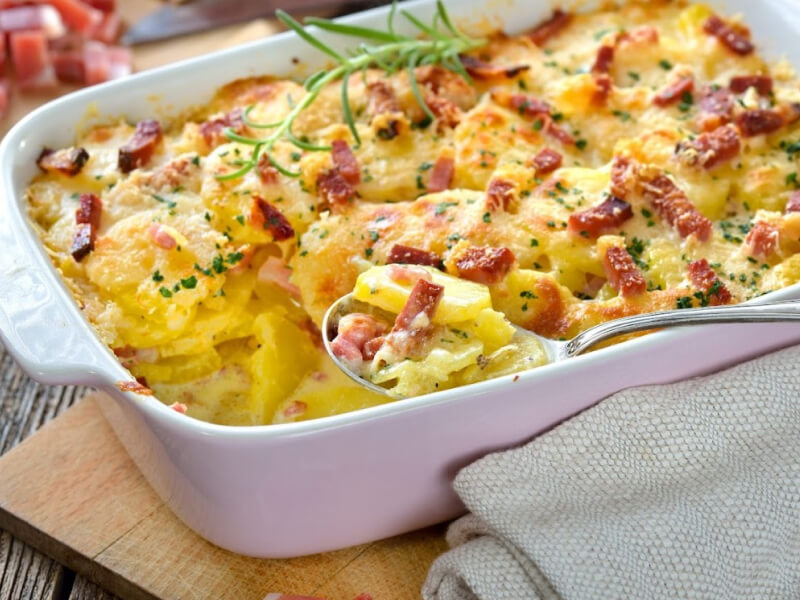 Spoon in an au gratin dish inside a white casserole pan Spoon in an au gratin dish inside a white casserole pan