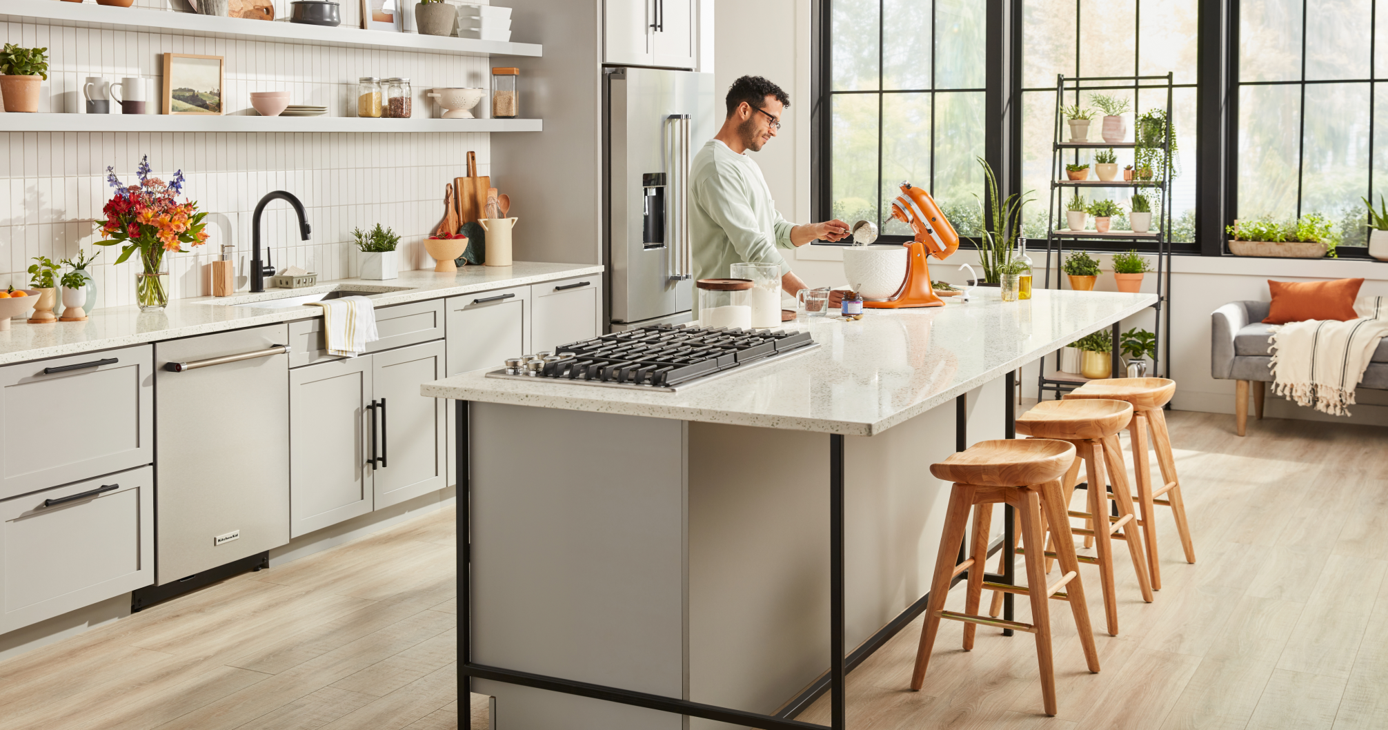 A man using a Honey KitchenAid® Stand Mixer on the island in a bright kitchen