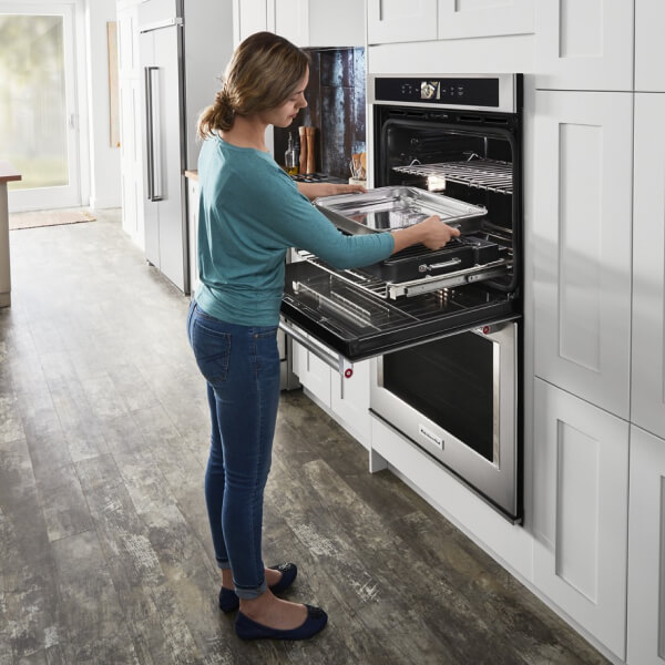Woman placing a roasting rack inside an oven