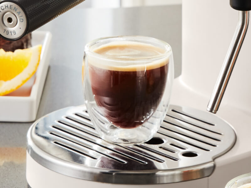 Finished espresso drink resting on cup holder of espresso machine