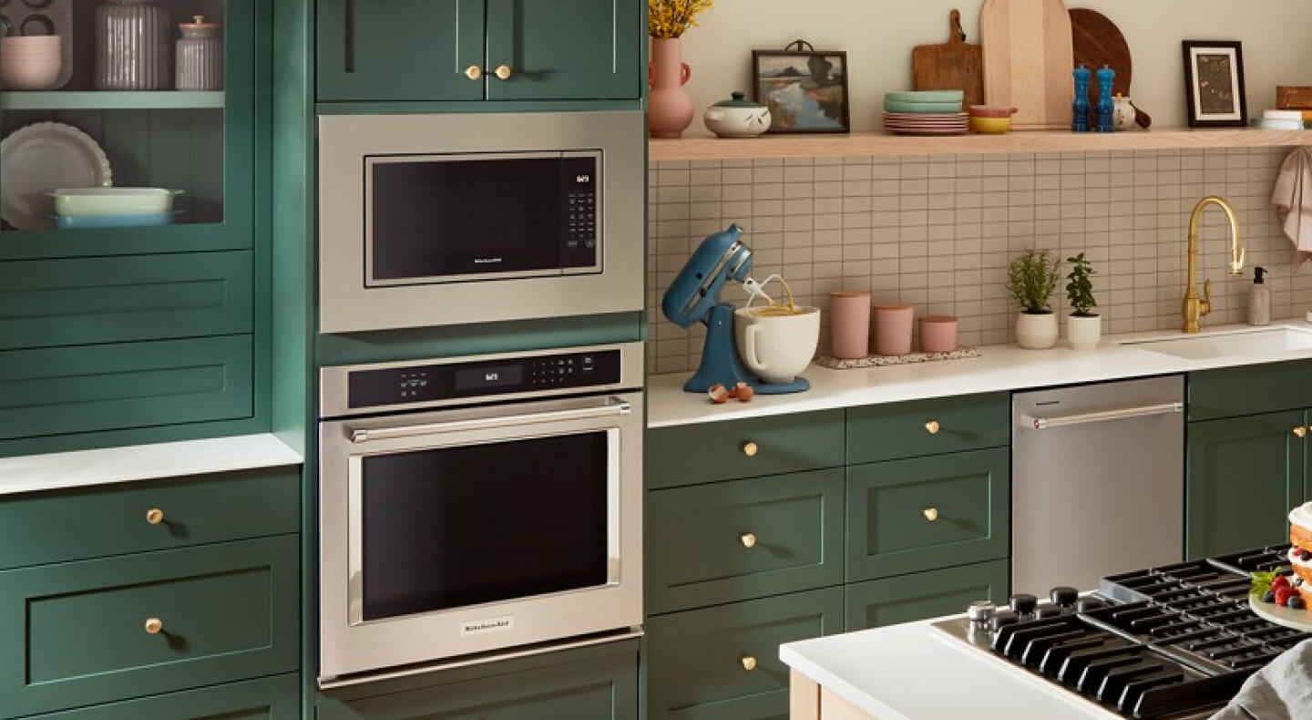 A built-in KitchenAid® microwave above a wall oven surrounded by teal cabinetry
