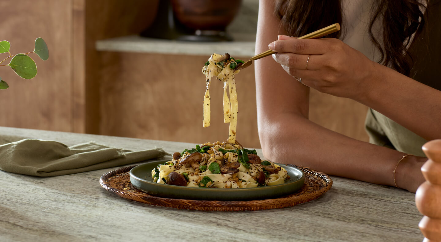 Close-up of person eating noodle dish off of olive green plate Close-up of person eating noodle dish off of olive green plate