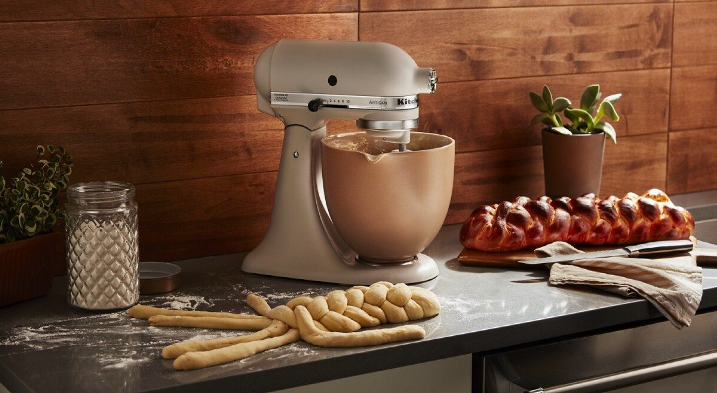 Matte gold KitchenAid® stand mixer next to twisted bread dough on counter