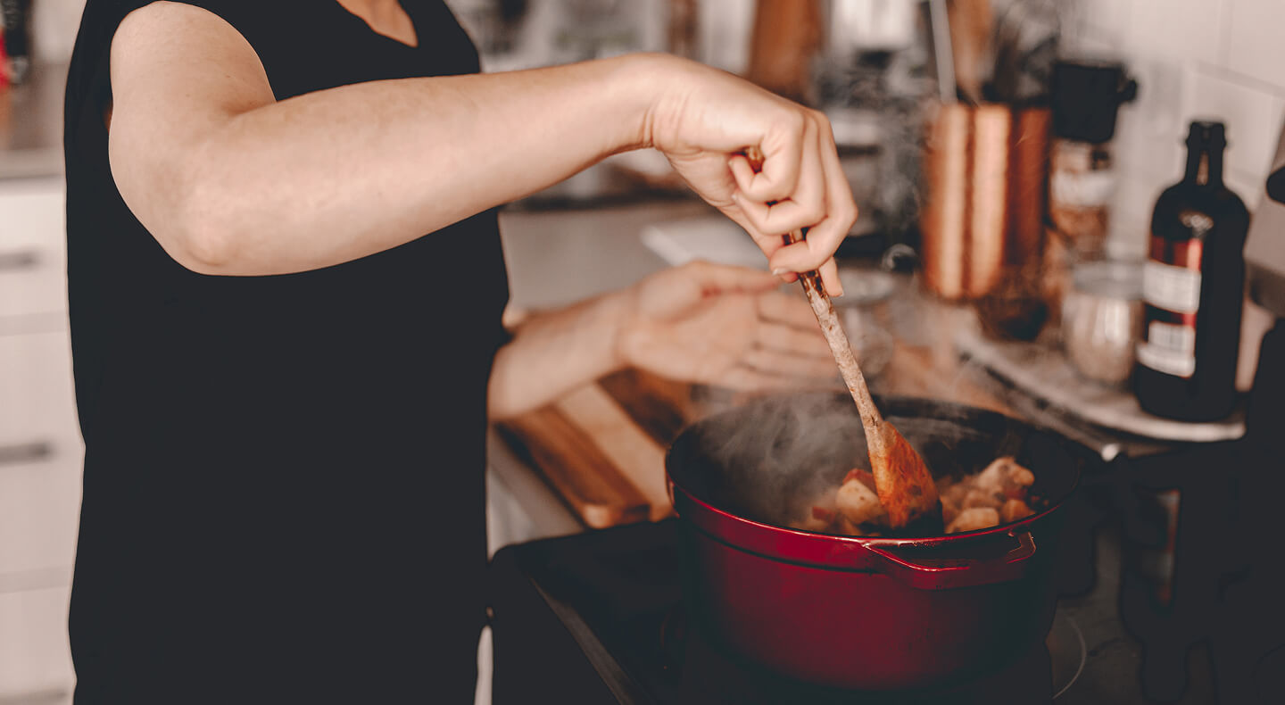 A person stirring a large Dutch oven on a stovetop
