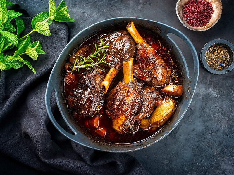 Lamb shanks braising inside of a Dutch oven