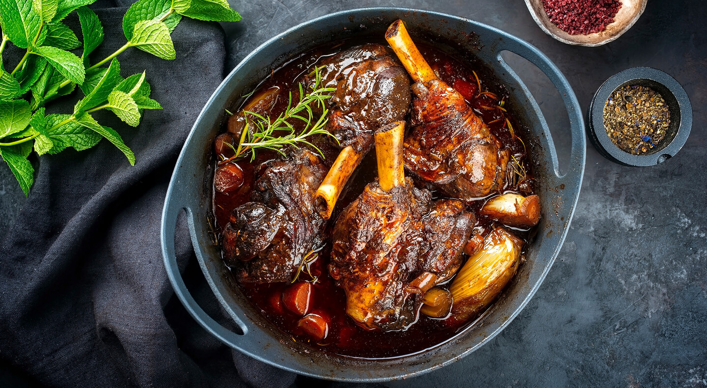 Lamb shanks braising inside of a Dutch oven