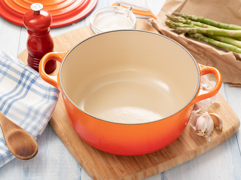 An orange Dutch oven surrounded by ingredients