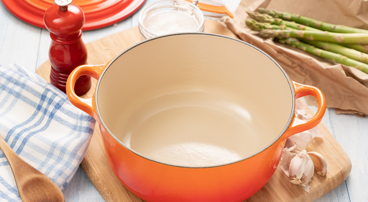 An orange Dutch oven surrounded by ingredients