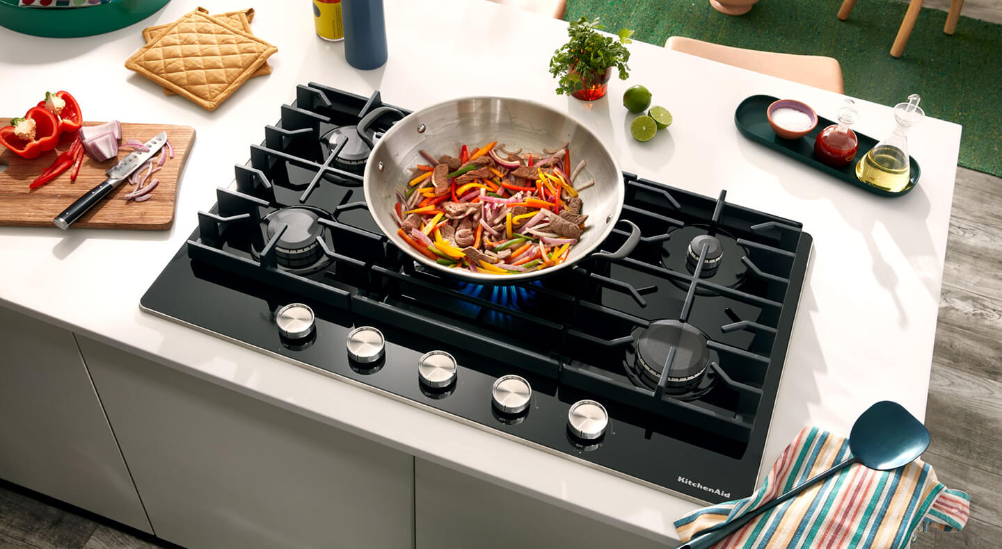 A cooktop with food cooking in a pan
