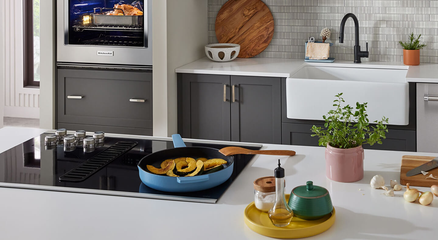 veggies in a pan on a cooktop installed in a kitchen island