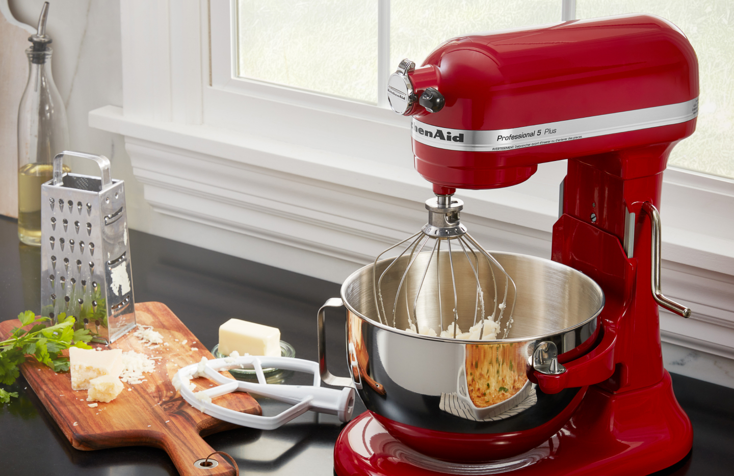 Red KitchenAid® stand mixer next to grated cheese and butter Red KitchenAid® stand mixer next to grated cheese and butter