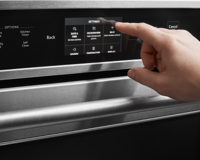Hand adjusting settings on an oven’s control panel