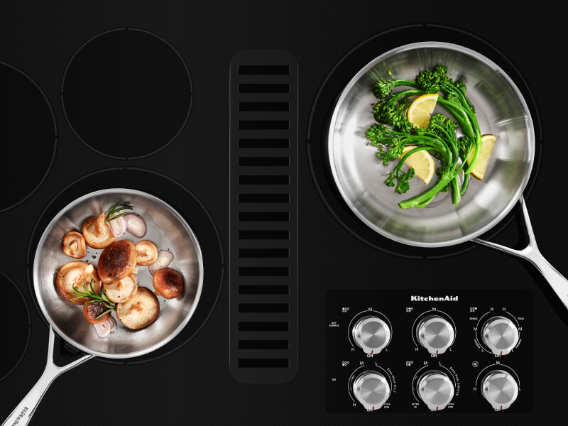 Two pans filled with vegetables on a cooktop Two pans filled with vegetables on a cooktop