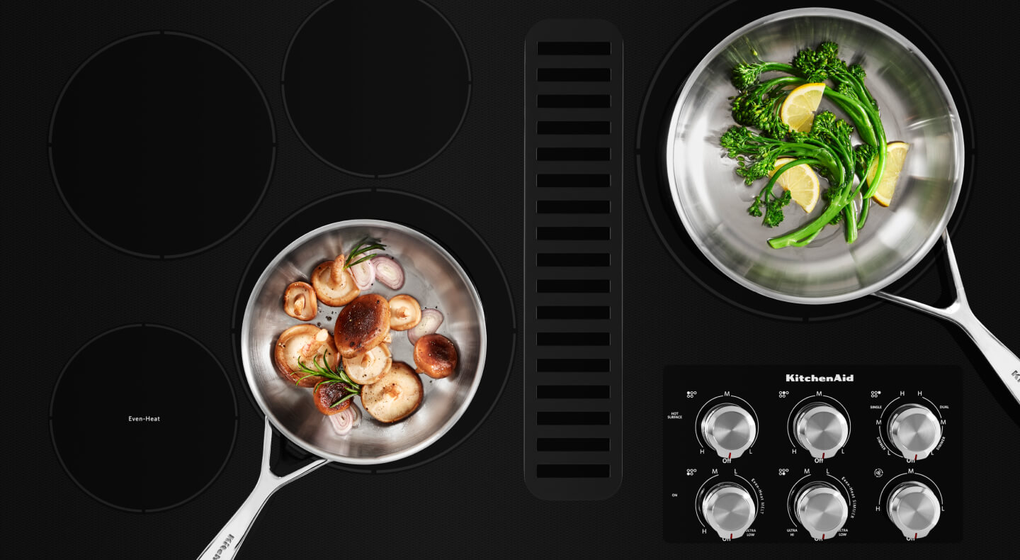 Two pans filled with vegetables on a cooktop Two pans filled with vegetables on a cooktop