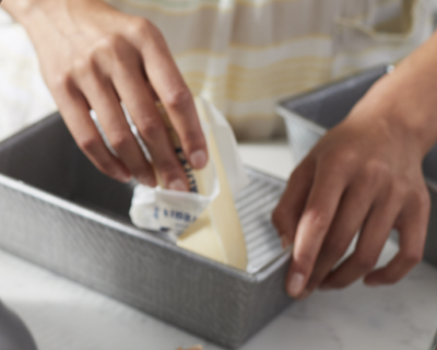 A person buttering a bread pan