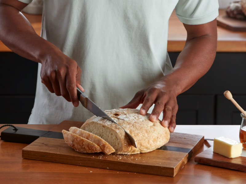 A person slicing bread next to an orange KitchenAid® stand mixer A person slicing bread next to an orange KitchenAid® stand mixer