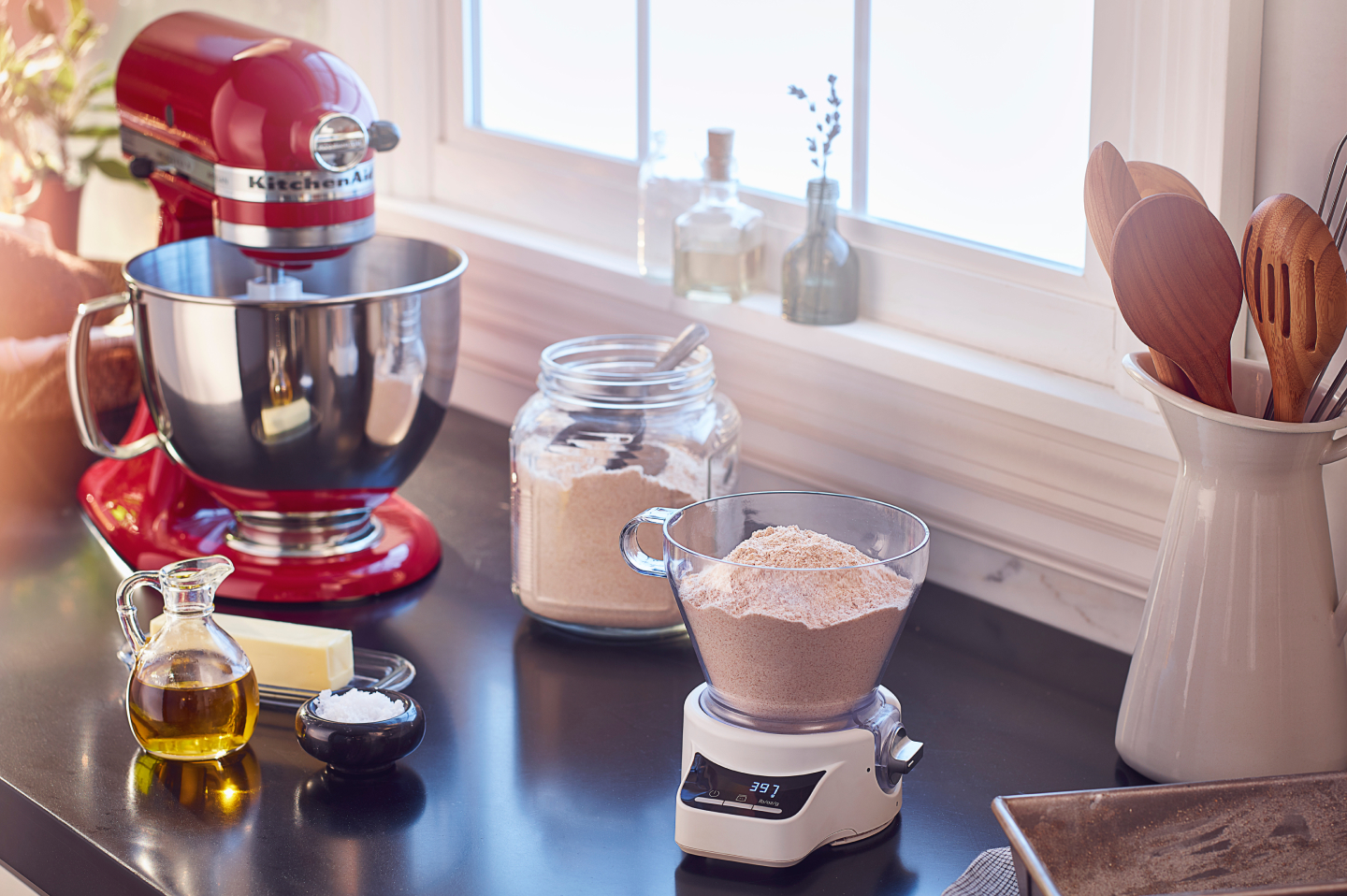 A red KitchenAid® stand mixer amongst a food scale and various baking ingredients A red KitchenAid® stand mixer amongst a food scale and various baking ingredients