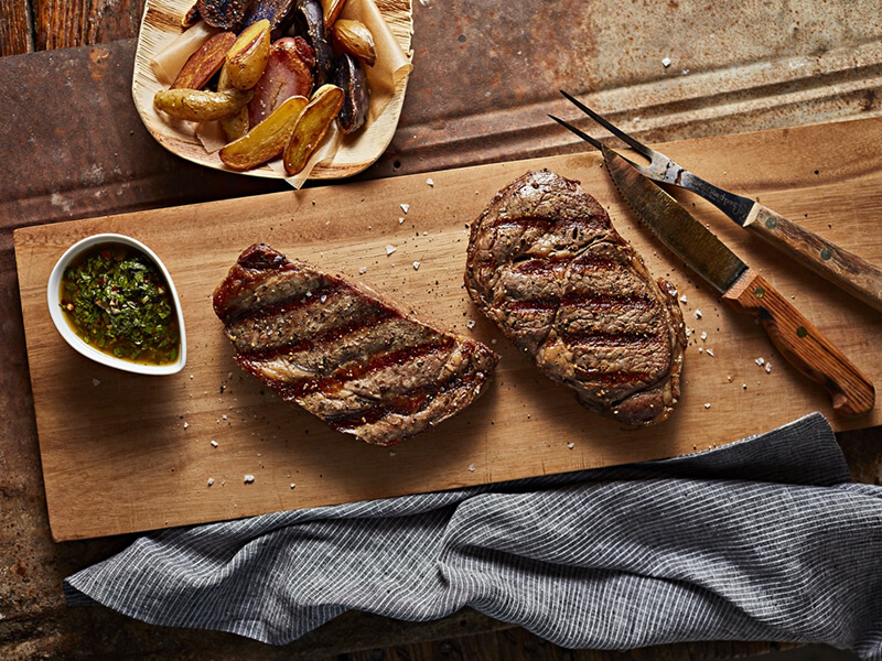 Two pieces of cooked steak on a cutting board Two pieces of cooked steak on a cutting board