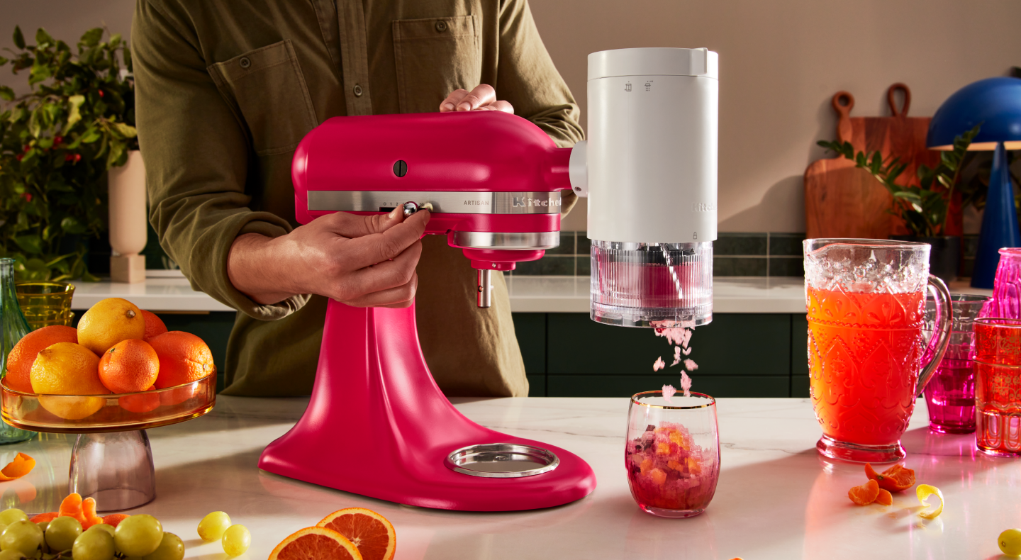 Pink KitchenAid® stand mixer with the KitchenAid®  Shave Ice Attachment shaving flavored ice into drink Pink KitchenAid® stand mixer with the KitchenAid®  Shave Ice Attachment shaving flavored ice into drink