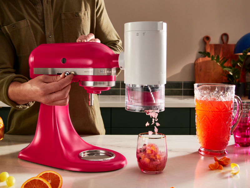 Pink KitchenAid® stand mixer with the KitchenAid®  Shave Ice Attachment shaving flavored ice into drink Pink KitchenAid® stand mixer with the KitchenAid®  Shave Ice Attachment shaving flavored ice into drink