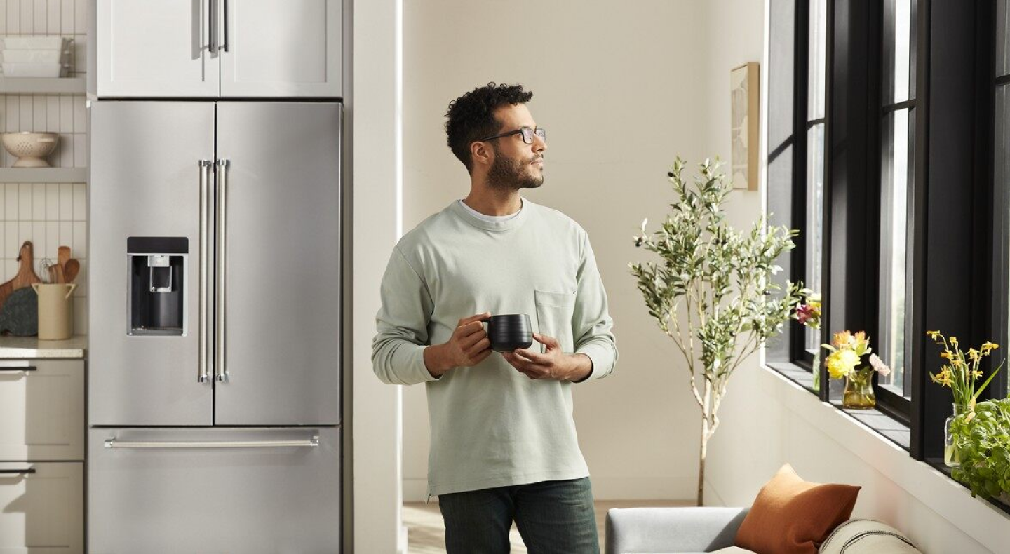 Person with mug standing in front of stainless steel French-door refrigerator Person with mug standing in front of stainless steel French-door refrigerator