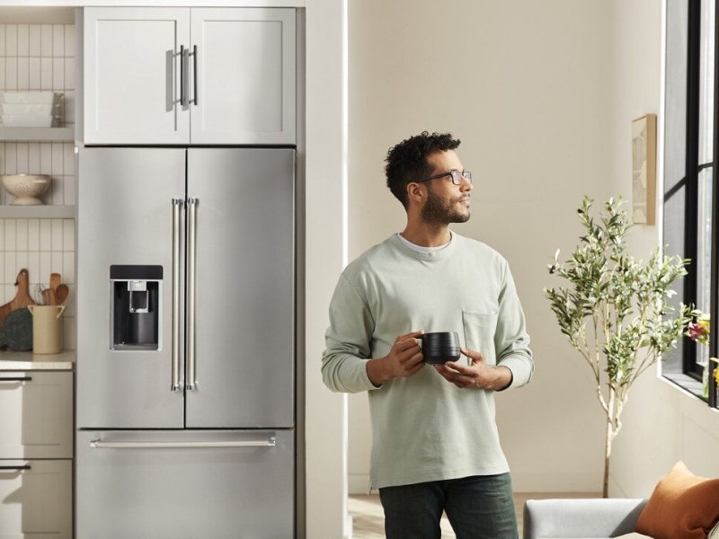 Person with mug standing in front of stainless steel French-door refrigerator Person with mug standing in front of stainless steel French-door refrigerator