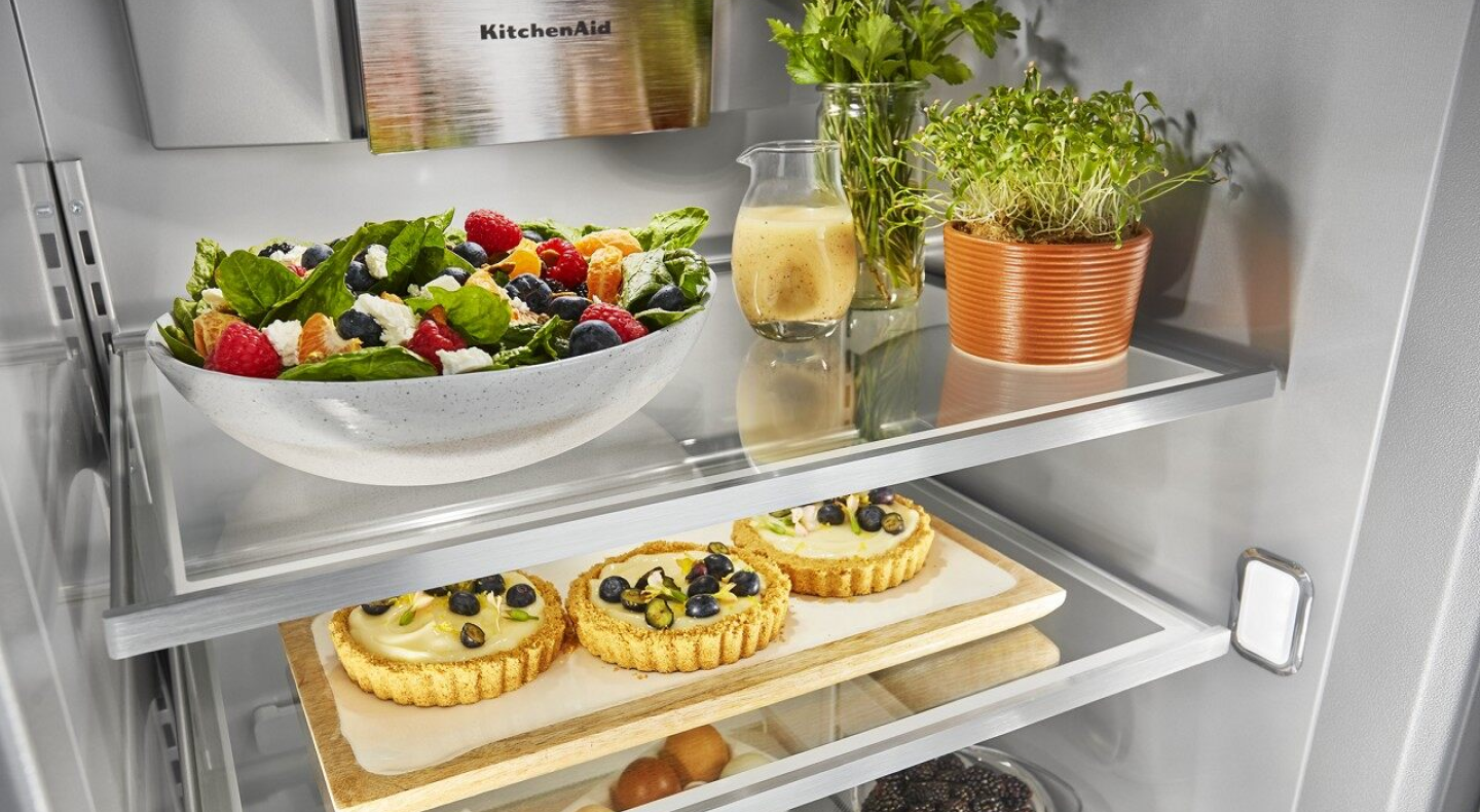 Food platters, herbs and tarts in an open refrigerator Food platters, herbs and tarts in an open refrigerator