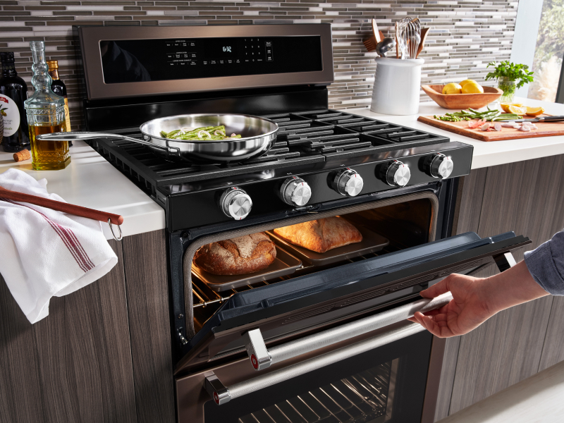 A person opening the oven door to check on baking bread A person opening the oven door to check on baking bread