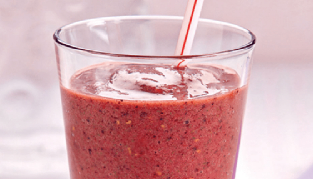 A red fruit smoothie in a glass.