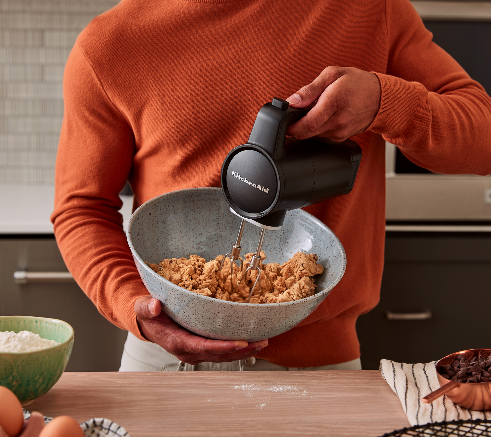 A person using the KitchenAid Go™ Cordless Hand Mixer to mix a bowl of cookie dough.