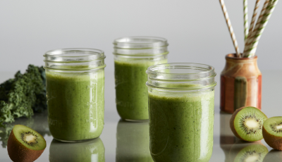 Green smoothies in jars surrounded by kiwis.