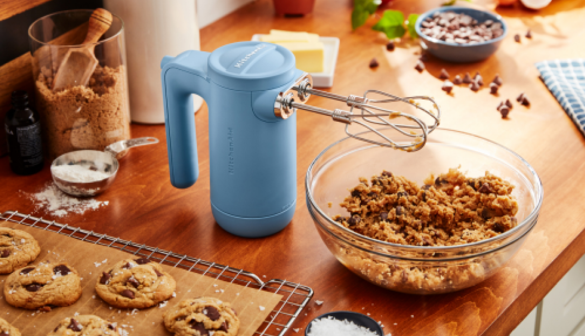 A Blue Velvet Cordless Hand Mixer standing upright over a bowl of cookie dough.