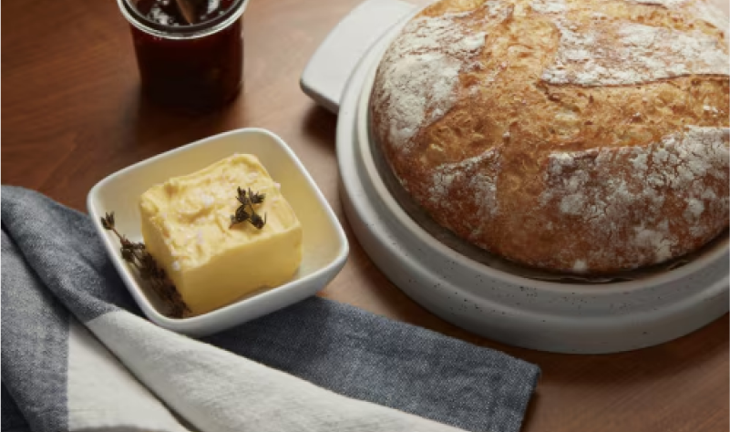 Butter next to a boule of bread.